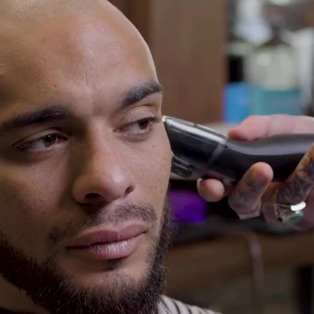 Man getting a haircut with an electric razor in a barbershop setting