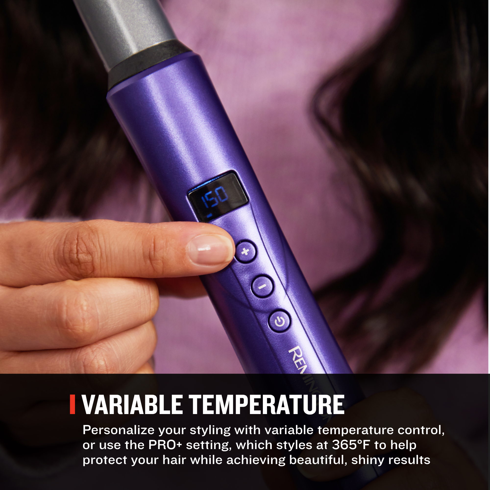 A close-up of a hand holding a purple curling wand with a digital temperature display, shown against a blurred background of dark hair and pink fabric. Text at the bottom reads 'VARIABLE TEMPERATURE' with descriptive copy.