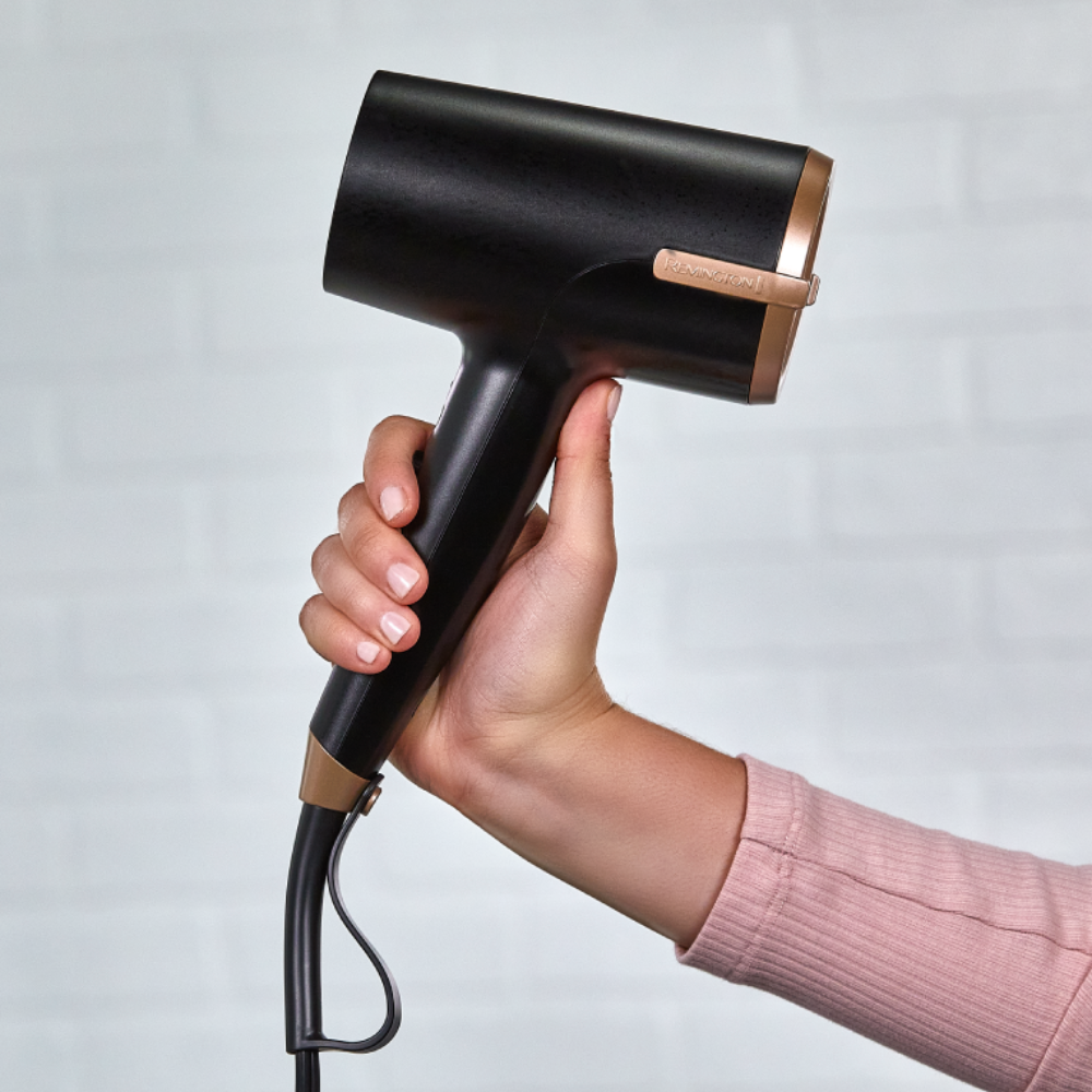 D31A10 Black hair dryer held in a hand against a light gray background