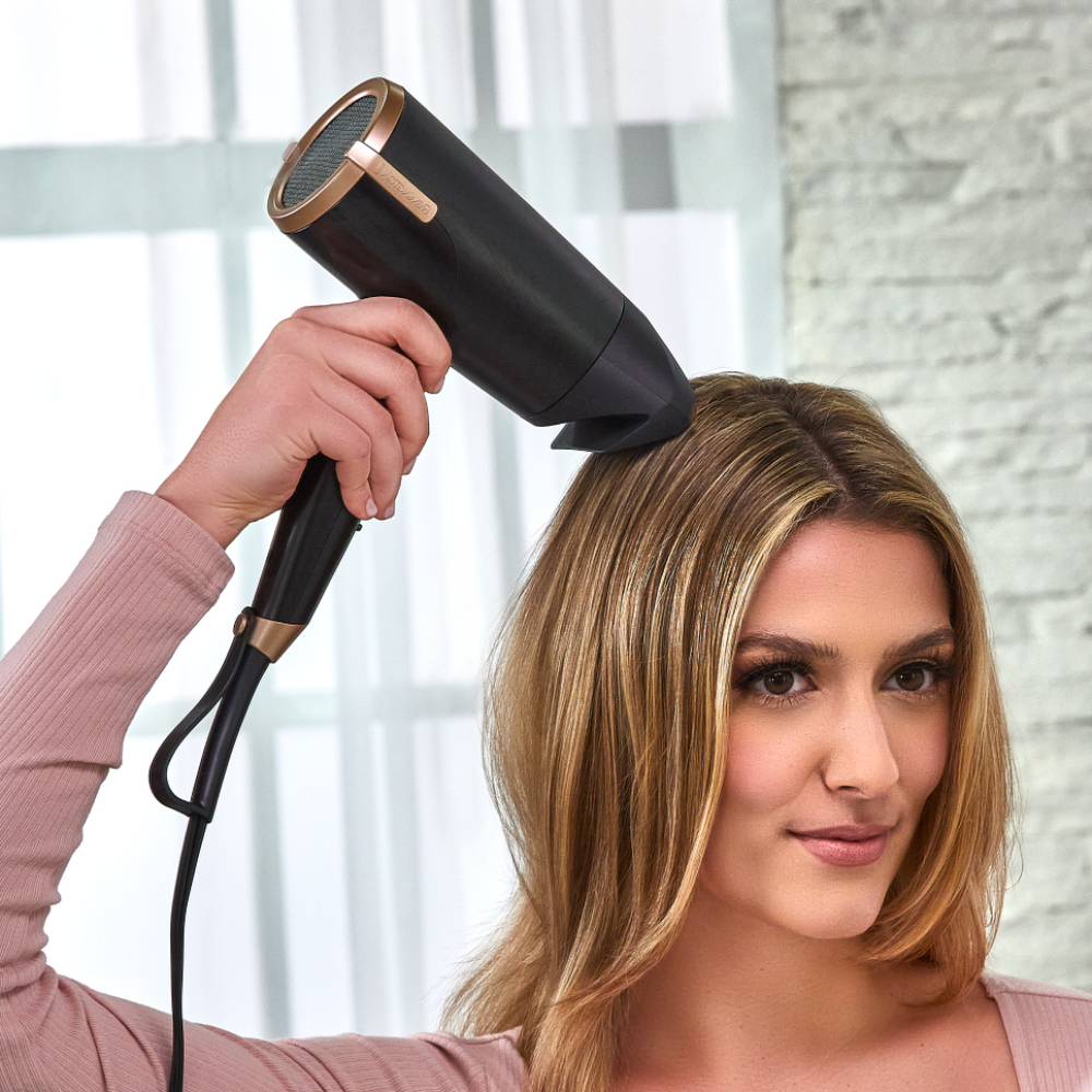 Woman using a black D31A10 hair dryer with a blurred background