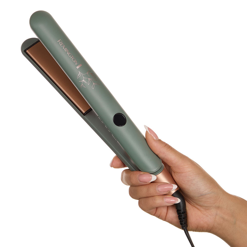 S5750NA Botanicals™ 1" Flat Iron held in a hand with a white background