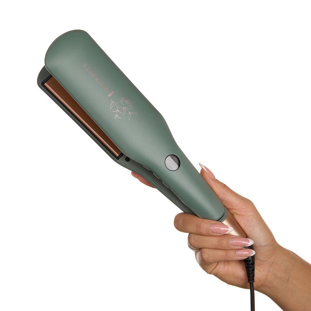 S5755NA Botanicals™ 2" Flat Iron held by a hand on a white background