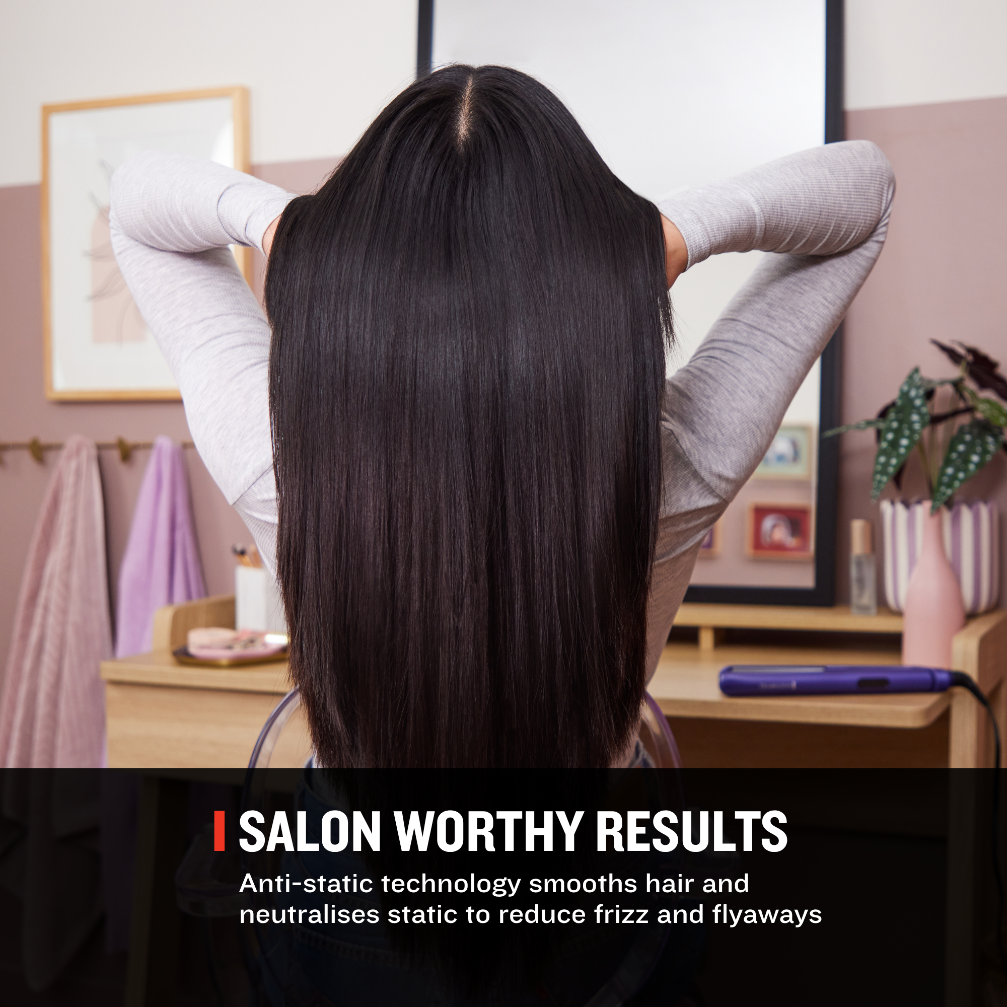 A woman seen from behind with long, straight, dark brown to near-black hair, wearing a light gray long-sleeve top in a salon-like interior. Text at the bottom reads 'SALON WORTHY RESULTS' with smaller descriptive copy about anti-static technology smoothing hair and reducing frizz and flyaways.