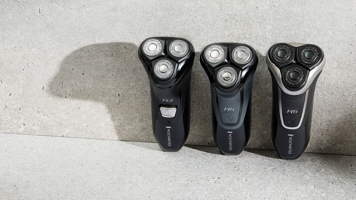 Three electric shavers on a concrete surface