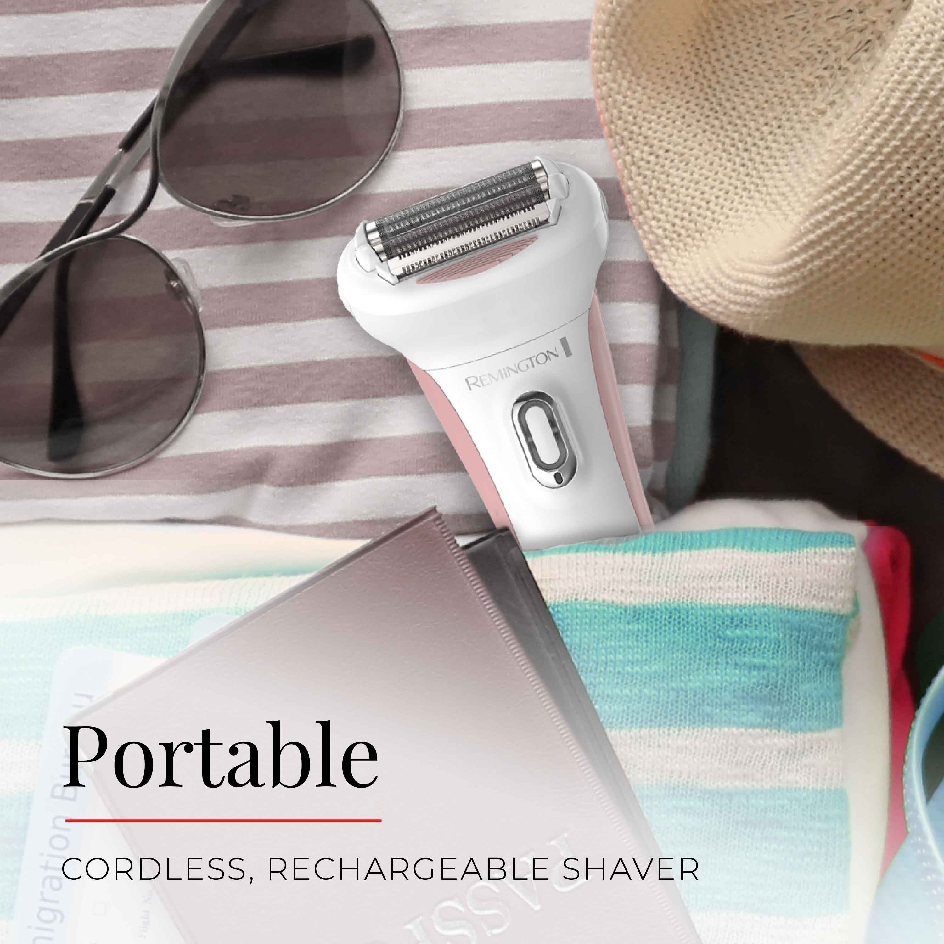 Portable cordless rechargeable shaver on a striped fabric background with sunglasses and a hat.