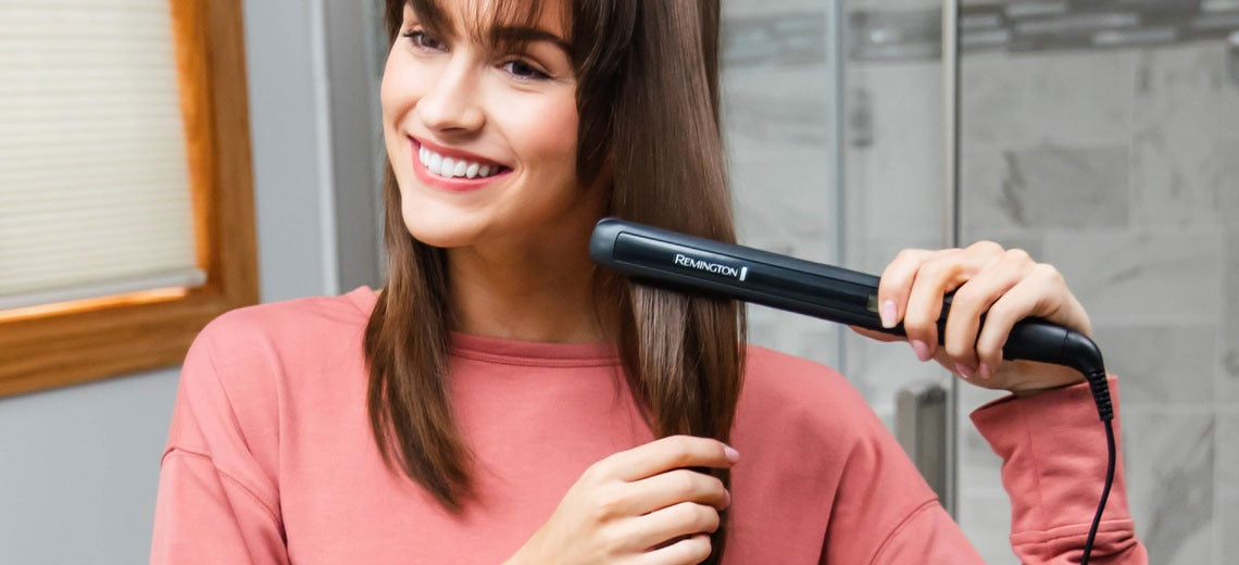 Woman with mid-length hair using flat iron