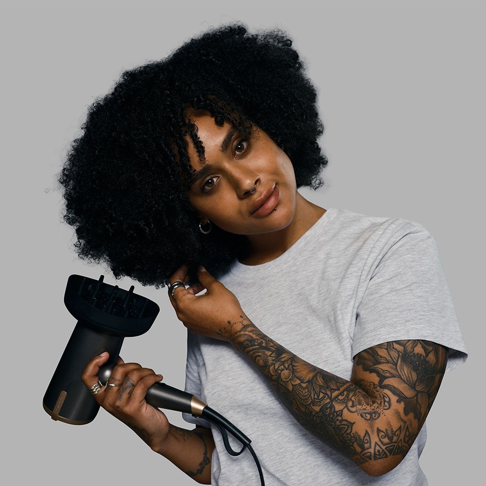 Woman with tattoos drying hair with diffuser attachment