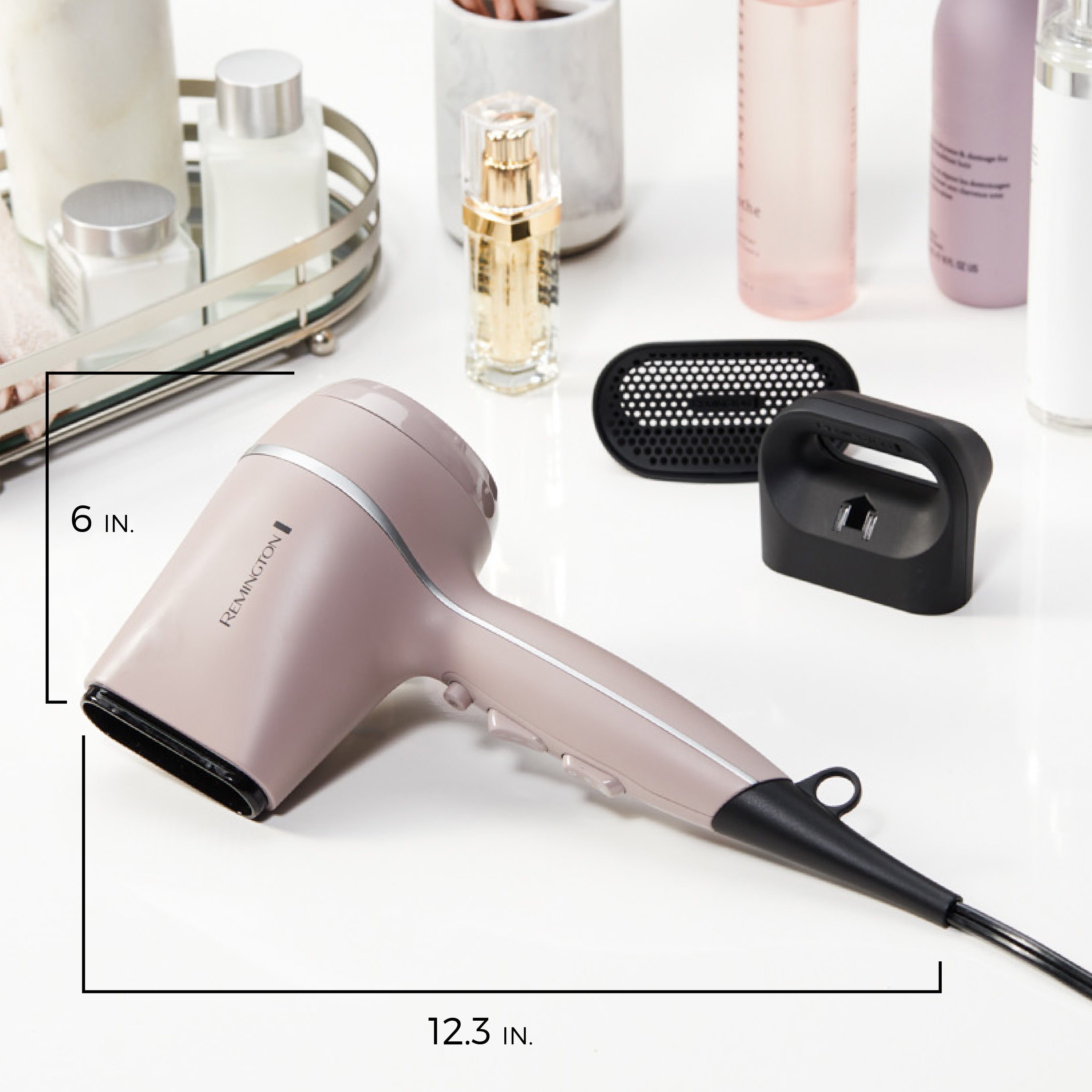 Pink hair dryer with attachments on a white surface with cosmetic products in the background