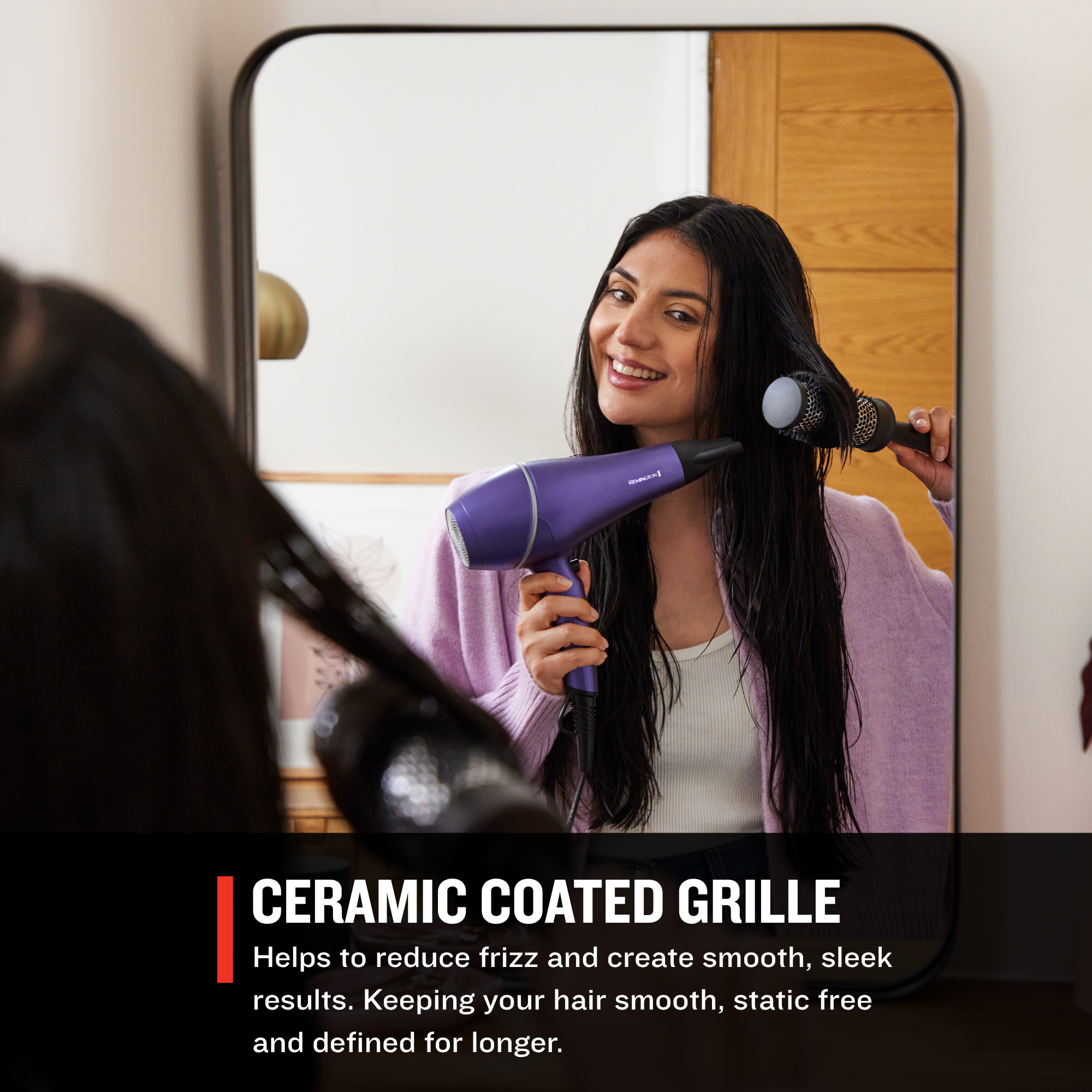 Woman using a AC9350US Gloss™ Hair Dryer  with a ceramic coated grille in front of a mirror.
