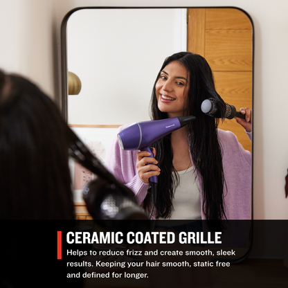 Woman using a AC9350US Gloss™ Hair Dryer  with a ceramic coated grille in front of a mirror.