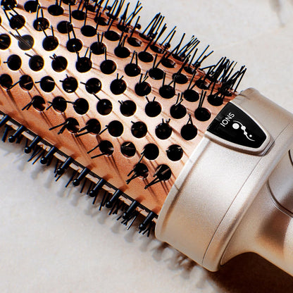 Hairbrush with wooden handle and black bristles, attached to a hair dryer on a light background