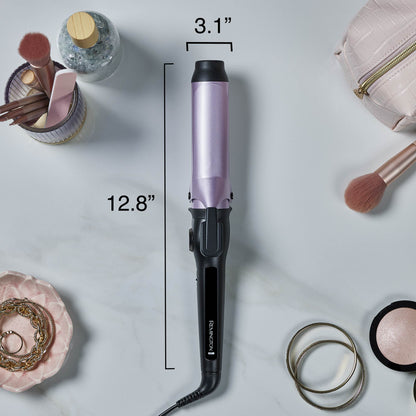 A hair curling iron with a lavender purple barrel and black handle, shown on a light marble background with cosmetic props around it. Black dimension lines indicate a barrel width of 3.1 inches.