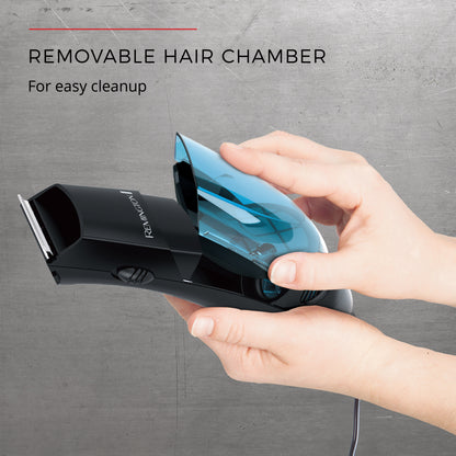 Hand holding a hair trimmer with a removable hair chamber on a gray background