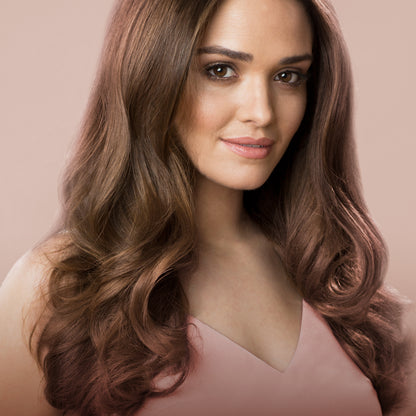 Woman with long, wavy brown hair against a beige background