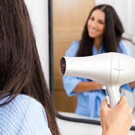 woman dryer hair in front of mirror