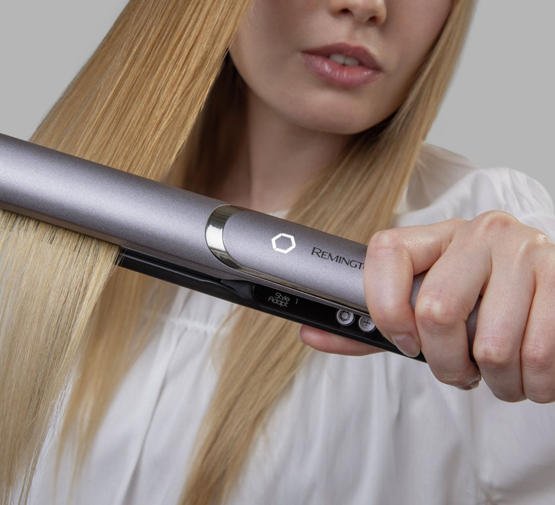 Woman straightening hair with flat iron