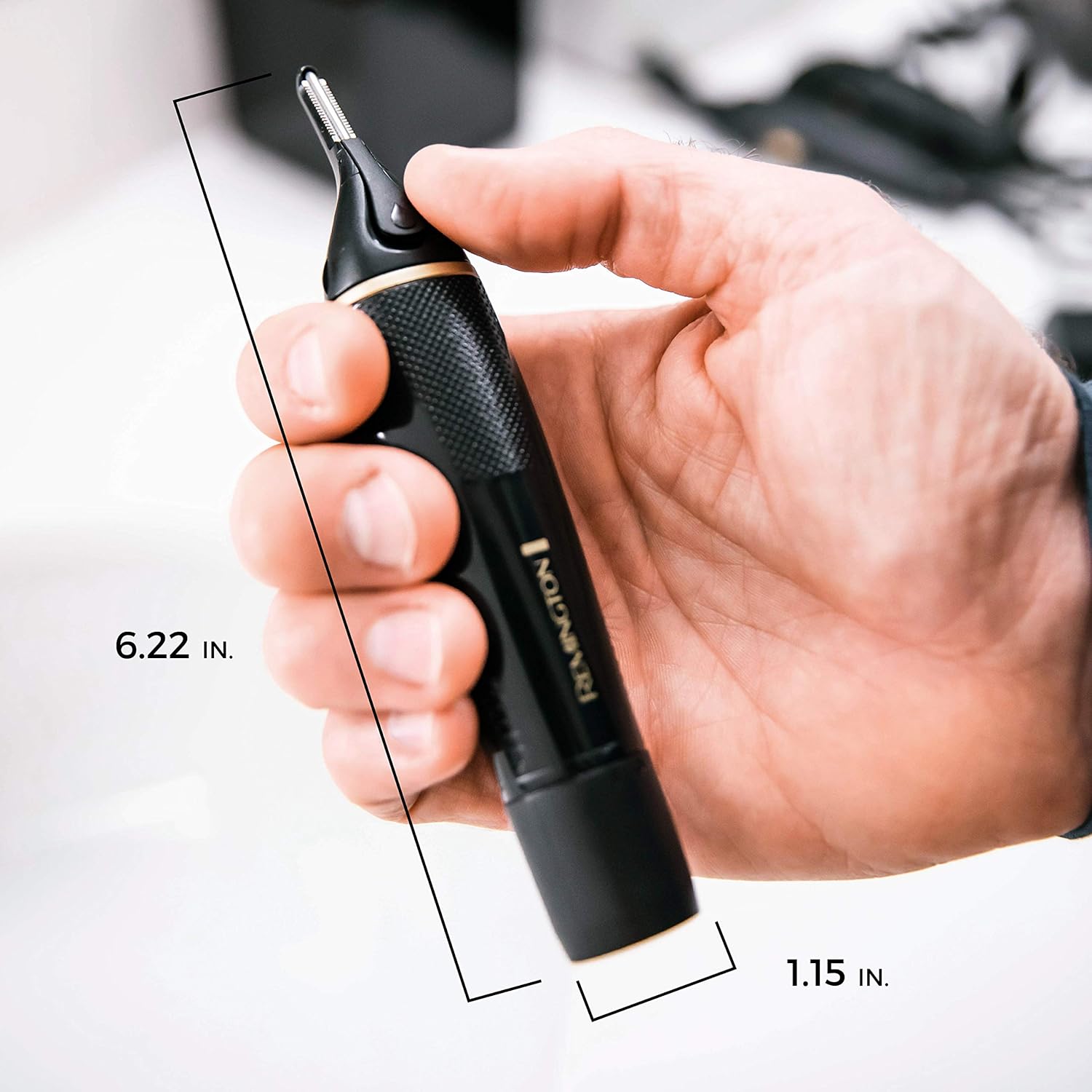 Hand holding a black electronic device with measurements indicated