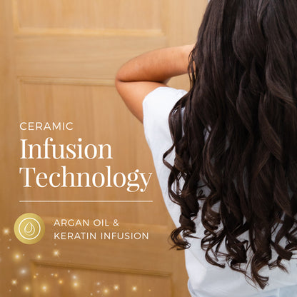 Person with long, wavy hair standing in front of a wooden door, with text about ceramic infusion technology and argan oil & keratin infusion.